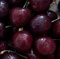 a bunch of plums with water droplets on them sitting in a pile next to each other