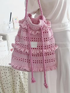 a pink crocheted purse hanging from a mannequin's headdress