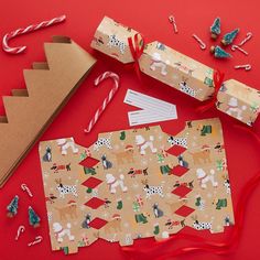 some wrapping paper and christmas decorations on a red surface