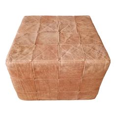 an ottoman made out of brown leather with squares on the top and bottom, sitting in front of a white background