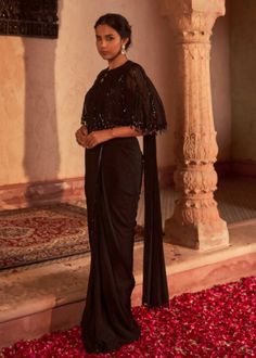 Elegant drape sari in crepe is paired with fully embroidered sequins and beaded georgette cape. The outfit is paired with padded silk blouse and embroidered belt. Cape Style Blouse For Saree, Saree With Cape Style, Saree Cape Blouse, Drape Saree With Cape, Cape Saree Design, Stylish Outfits For Wedding Guests, Black Western Blouse, Black Saree With Jacket, Cape On Saree