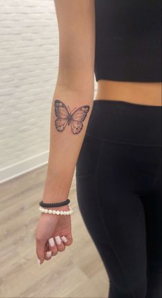 a woman's arm with a butterfly tattoo on the left side of her wrist