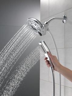 a person is holding the shower head in their hand and it's spraying water