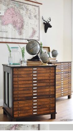 an old dresser with drawers and globes on it in front of a large map