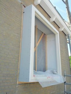 an unfinished window being installed on the side of a brick building with scaffolding around it