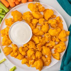 a white plate topped with cauliflower next to carrots and celery