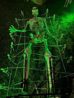 a green skeleton is in the grass with its arms and legs spread out, while it's surrounded by wires