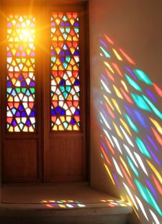 two stained glass windows with different colors and shapes in the same room, one is casting a shadow on the wall