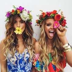 two beautiful women standing next to each other with flowers in their hair and wreaths on their heads