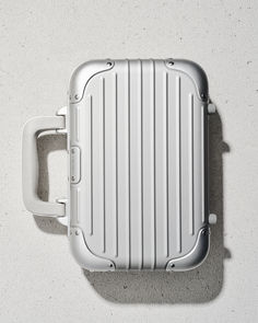 an overhead view of a white suitcase on the ground with its lid open and handle extended