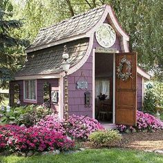 a small purple house with pink flowers in the front yard