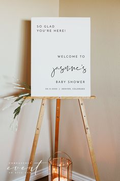 a welcome sign sitting on top of a wooden easel next to a lit candle