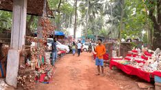 a man walking down a dirt road next to a market