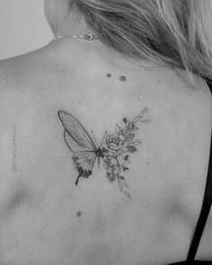 a black and white photo of a woman's back with a butterfly tattoo on it