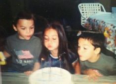 three children blowing out the candles on a cake