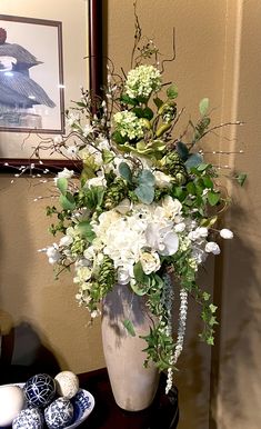 a vase filled with white and green flowers on top of a table next to an egg