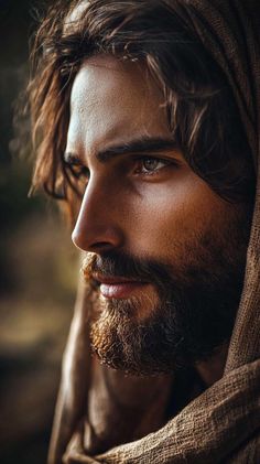 a man with long hair and beard wearing a shawl looking to the side, close up