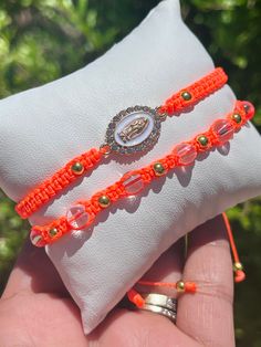 two orange bracelets are sitting on top of a white pillow in someone's hand