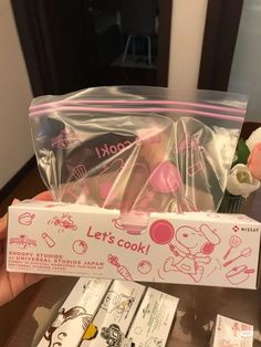 someone holding up a hello kitty cookie in a plastic bag with pink writing on it