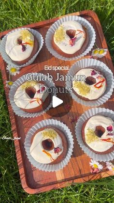 several cupcakes with white frosting and sprinkles on a wooden tray