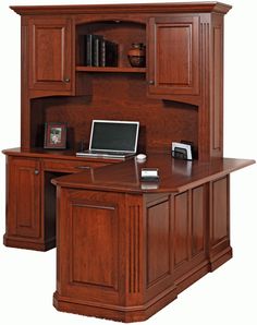 a wooden desk with a laptop computer on top of it, and cabinets above the desk