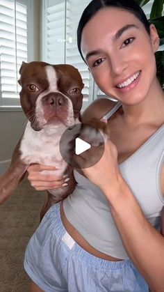 a woman holding a brown and white dog in her arms while smiling at the camera