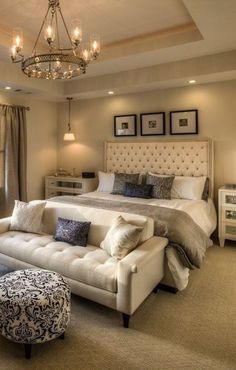 a bedroom with a large bed, couch and chandelier hanging from the ceiling