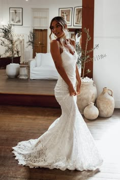 a woman in a white wedding dress posing for the camera with her hand on her hip