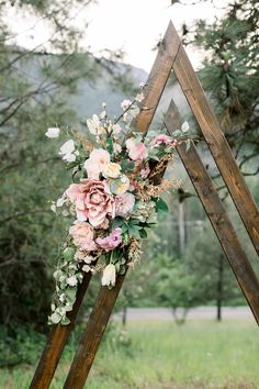 a wedding arch decorated with flowers and greenery for an outdoor ceremony in the woods