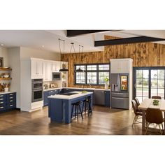 a large kitchen with wooden walls and white cabinets, blue island countertops, and an open floor plan