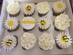 there are many cupcakes in the box that have flowers on them and bees