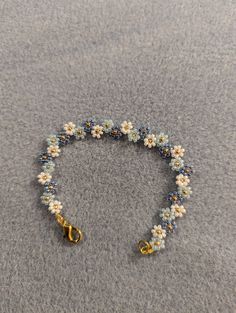 a beaded bracelet with flowers and scissors on the ground in front of a gray background