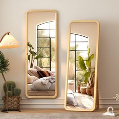 two large mirrors sitting on top of a table next to a potted plant and lamp