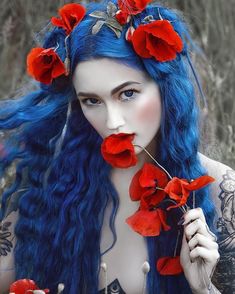 a woman with blue hair and red flowers in her hair