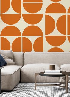 a living room with an orange and white pattern on the wall behind a gray couch