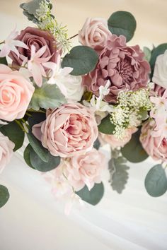 a bouquet of pink flowers sitting on top of a white cake covered in greenery