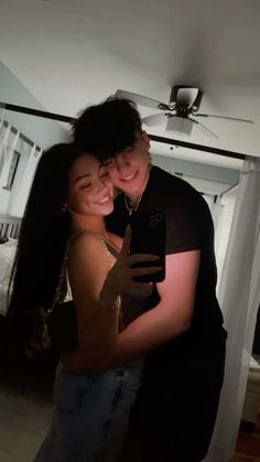 a man and woman hugging in front of a ceiling fan