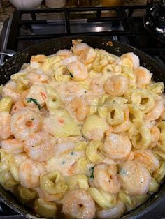 a pan filled with pasta and shrimp on top of a stove