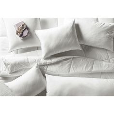 the comforter is made up with white pillows and blankets on top of each other