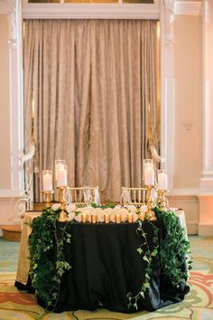 an elegant table with candles and greenery is set up in front of a window