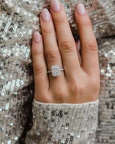 a woman's hand with a diamond ring on her finger and silver sequins