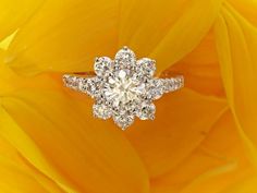 a diamond ring sitting on top of a yellow flower with the center surrounded by smaller diamonds