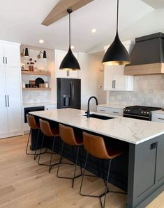 a large kitchen with an island and bar stools next to the stove top oven