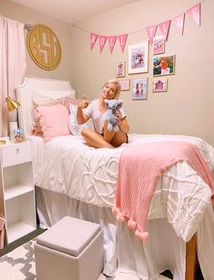 a woman sitting on top of a bed holding a stuffed animal in her hand and smiling