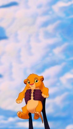 the lion king is sitting on his hind legs in front of a blue sky with clouds