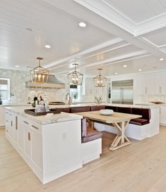 a large open kitchen with white cabinets and wood flooring, along with an island