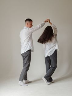 a man and woman dancing together in an empty studio area with white walls behind them