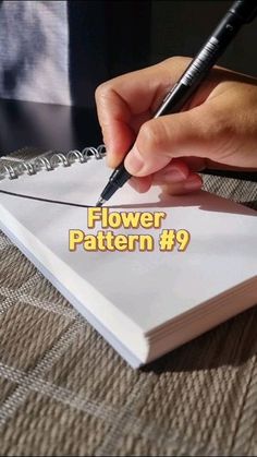 a person holding a pen writing on top of a book with the title flower pattern 9