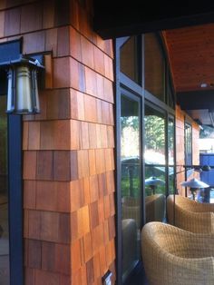 the outside of a restaurant with chairs and lamps on the side of the building that is made out of wood