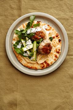 a white plate topped with meatballs and veggies on top of a table